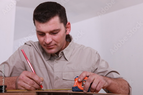 Tradesman marking a measurement with a pencil