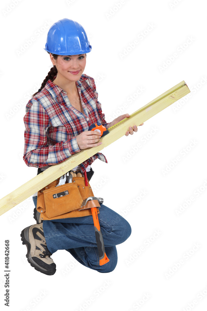 Female carpenter measuring timber Female carpenter measuring timber