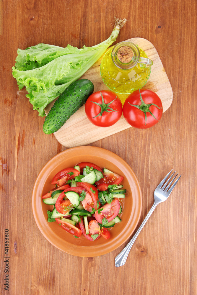 Fresh salad with tomatoes and cucumbers on wooden background Fresh salad with tomatoes and cucumbers on wooden background