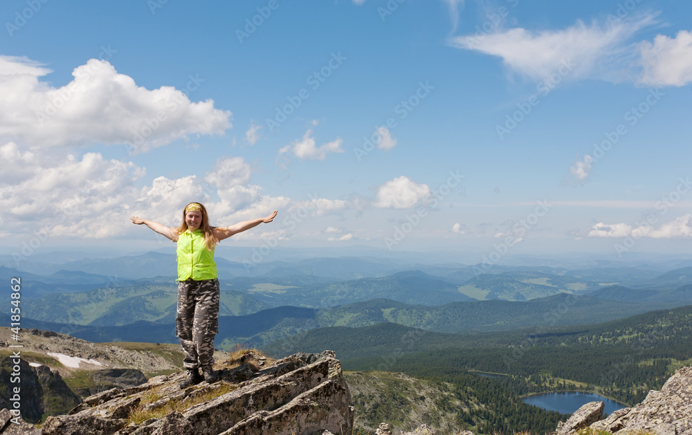 Fototapeta premium girl tourist to stand on rock, having stretched hands