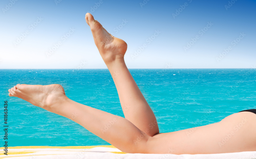 sexy female legs against turquoise sea sexy female legs against turquoise sea