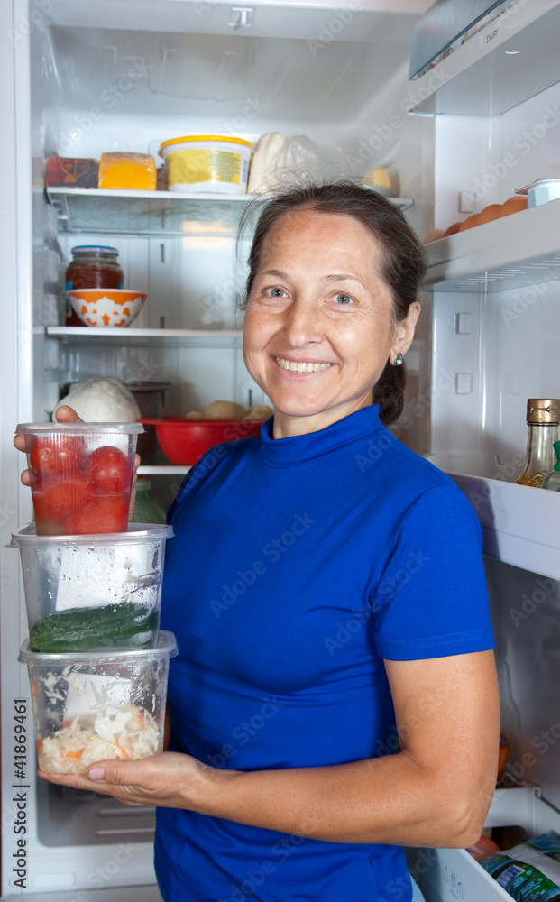 woman with vegetables near the fridge woman with vegetables near the fridge