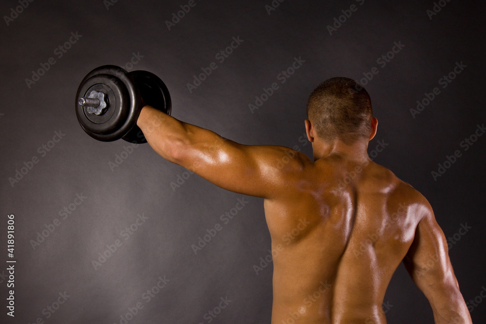Muscled male bodybuilder dumbbell swing Muscled male bodybuilder dumbbell swing