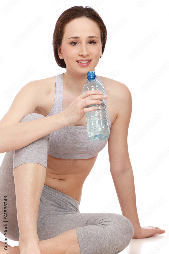 A sportive girl sitting on the floor with a bottle of water A sportive girl sitting on the floor with a bottle of water