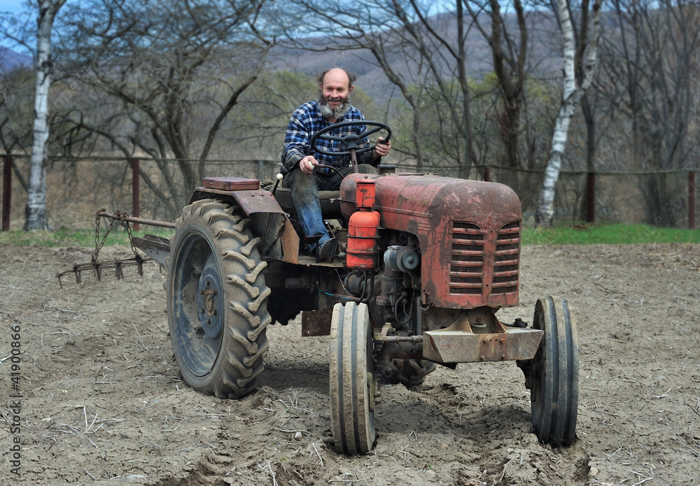 the bearded farmer establishes a plow on a tractor. Tractor on an arable land the bearded farmer establishes a plow on a tractor. Tractor on an arable land