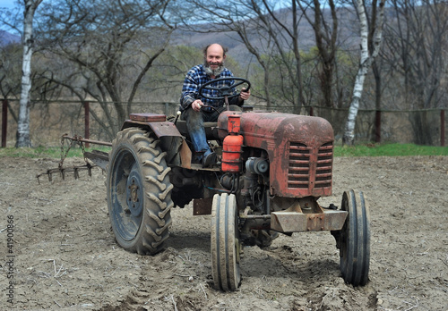 the bearded farmer establishes a plow on a tractor. Tractor on an arable land 