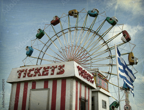 Aged and worn vintage photo of ferris wheel and ticket booth