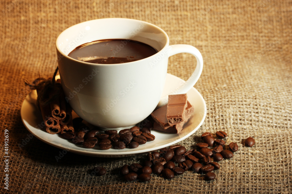 Obraz premium cup of coffee, beans and chocolate on sacking background