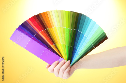 hand holding bright palette of colors on yellow background © Africa Studio