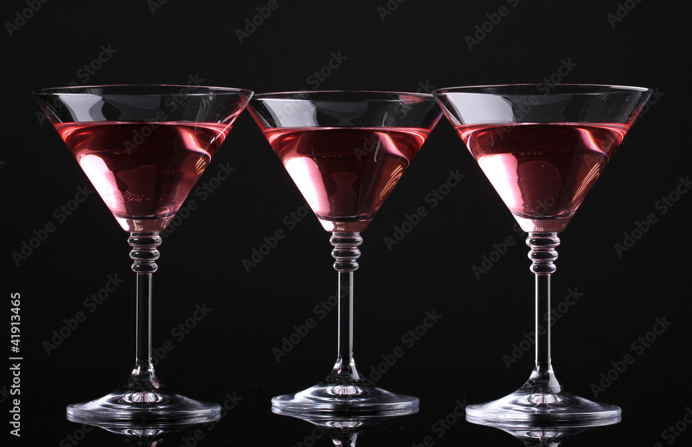 Red cocktail in martini glasses isolated on black Red cocktail in martini glasses isolated on black