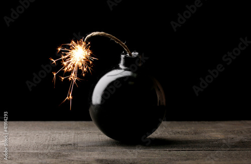 Fototapeta Cartoon style bomb on wooden table on black background