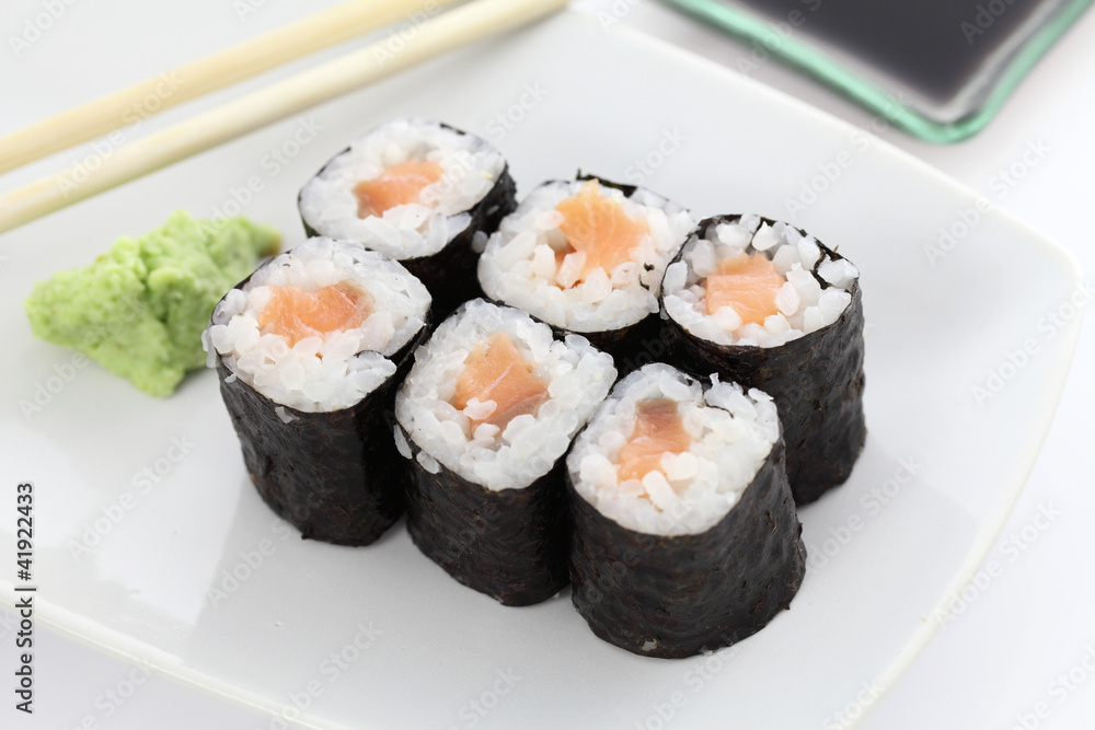 Salmon Maki sushi with chopsticks and soy sauce in white backgro