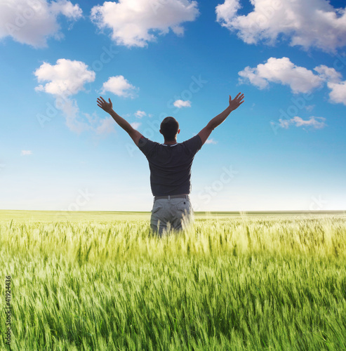 man standing on the green field under blue sky