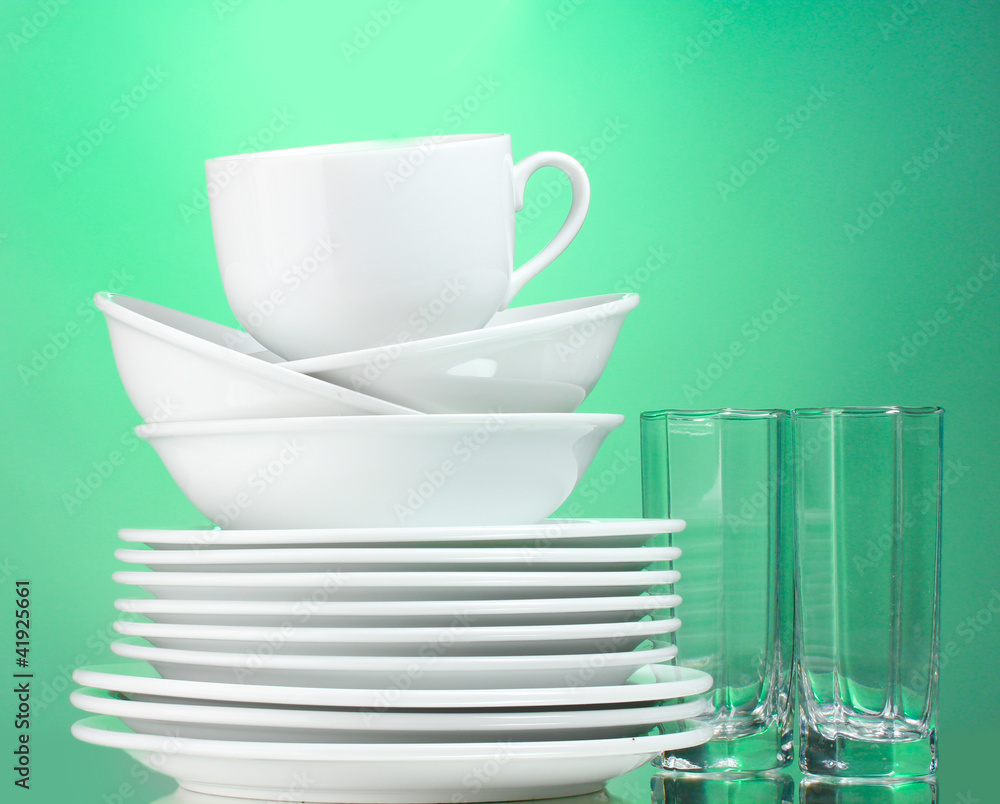 Clean plates, cup and glasses on green background Clean plates, cup and glasses on green background