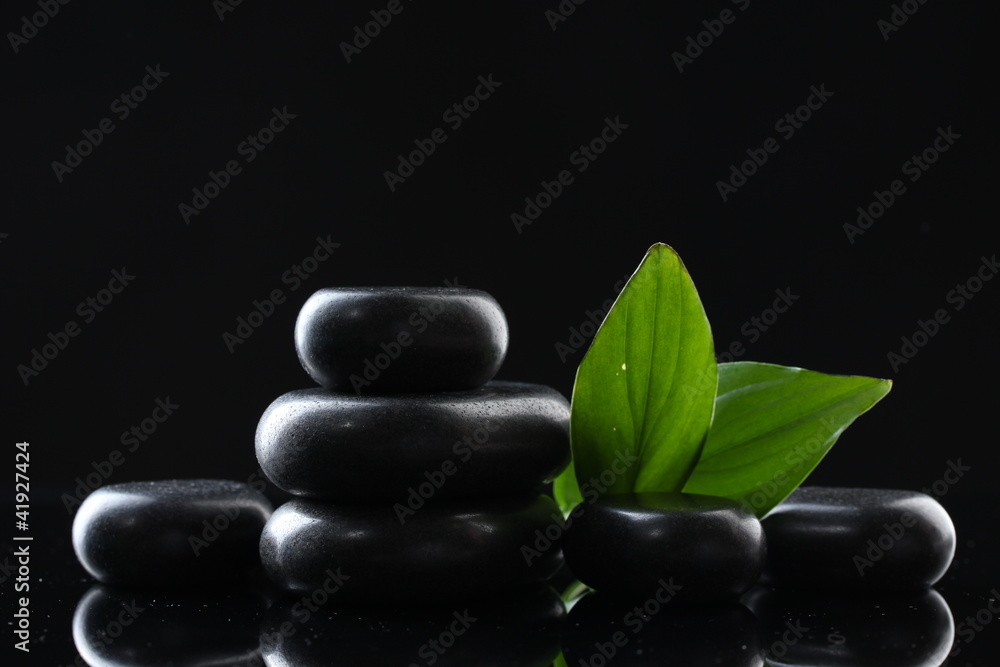 Obraz premium Spa stones and green leaves on black background