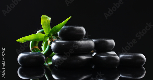 Spa stones and green bamboo on grey background