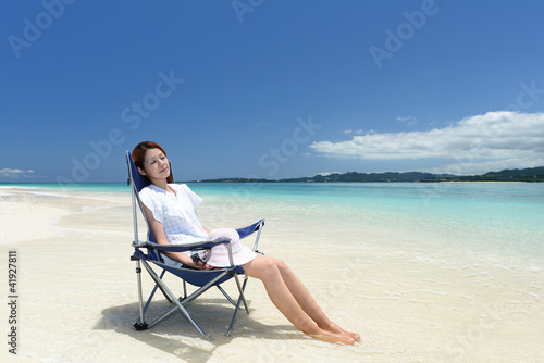 ビーチチェアに座り寛ぐ女性 © sunabesyou