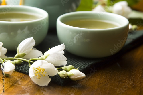 Green tea with jasmine in cup and teapot on wooden table