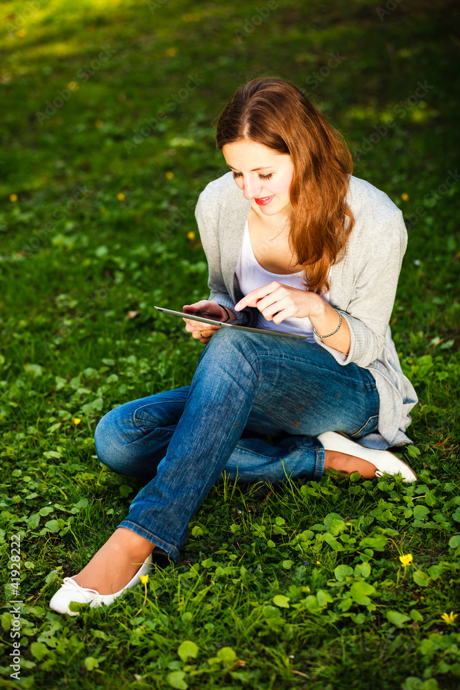 Young woman using her tablet computer while relaxing outdoors Young woman using her tablet computer while relaxing outdoors