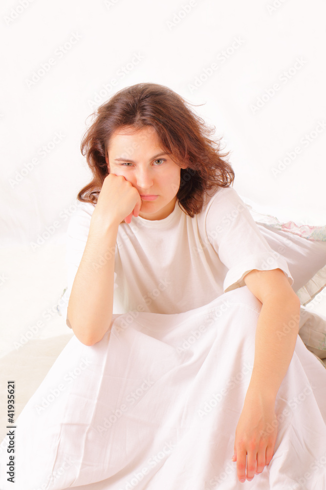 Serious young woman sitting in bed Serious young woman sitting in bed