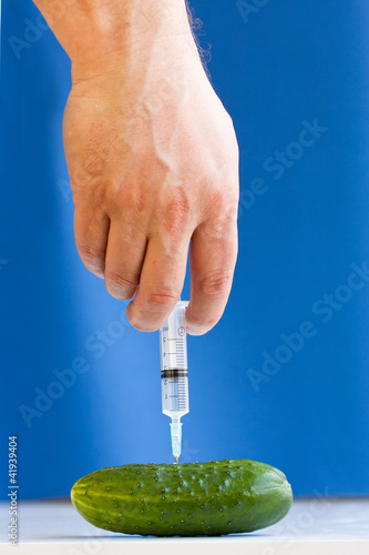 Hand making injection with syringe to cucumber