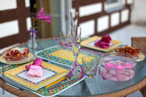 Table setting in pink on a balcony with fresh tomato salad