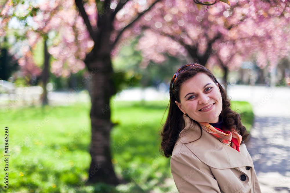 Happy young woman in spring garden with sakura on background Happy young woman in spring garden with sakura on background