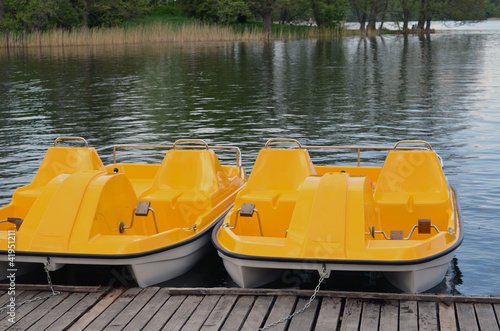 Yellow water bicycles locked at lake pier
