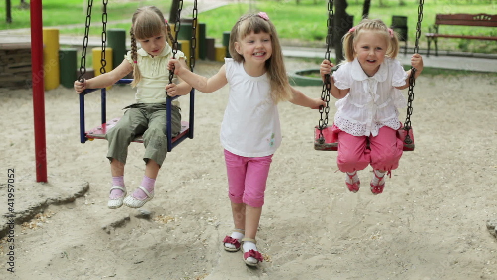 Three girls laughing child on a swing Three girls laughing child on a swing