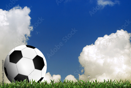 Football in green grass with cloud background