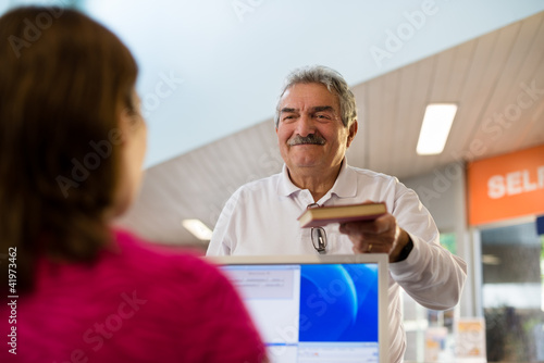 girl and senior man returning book in library