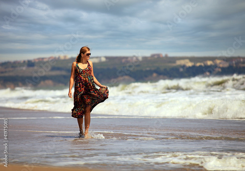 Young Caucasian woman walking along a beach