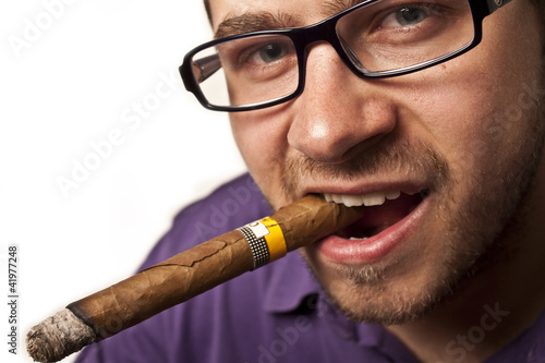 Młody mężczyzna w okularach palący cygaro