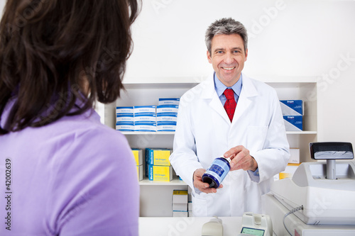 Doctor showing a pill container at drug store