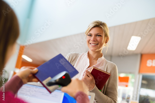 Tablou pe pânză girl returning book to librarian in library