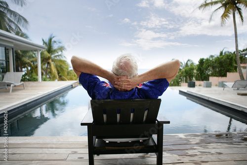 Картината върху платно Older man relaxing by a luxurious pool