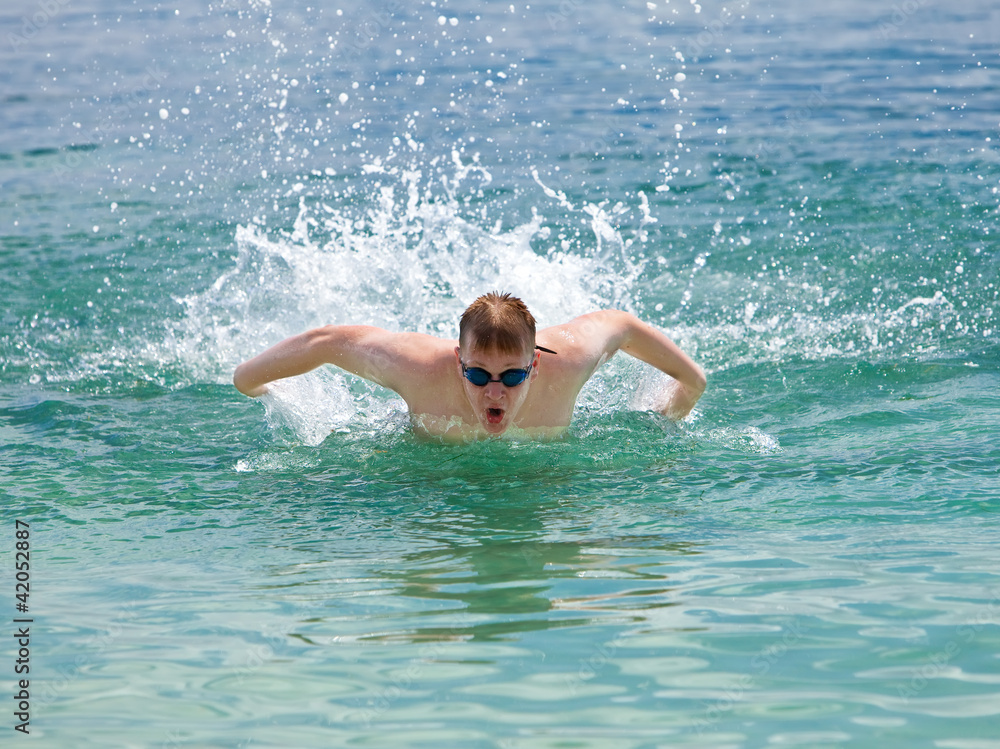young sporting man swims in the sea dolphin style. ..