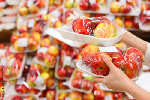 girl hands hold packed apples in store; photo