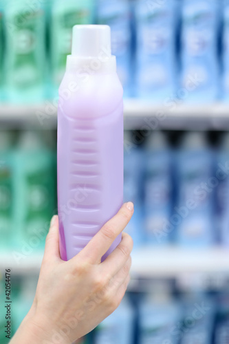 Woman hand holds bottle with abstergent in shop; photo