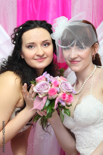 two young brides wearing white dresses hold beautiful bouquet photo