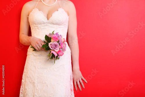 hands of bride wearing long white dress hold bouquet of roses photo