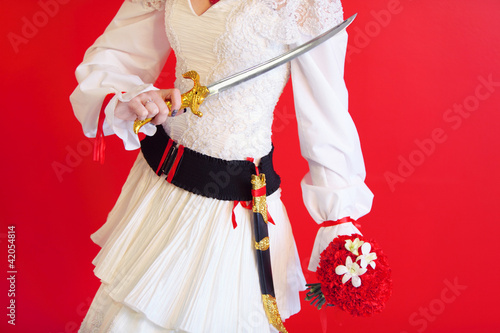 hands of bride wearing white dress with beautiful dagger photo