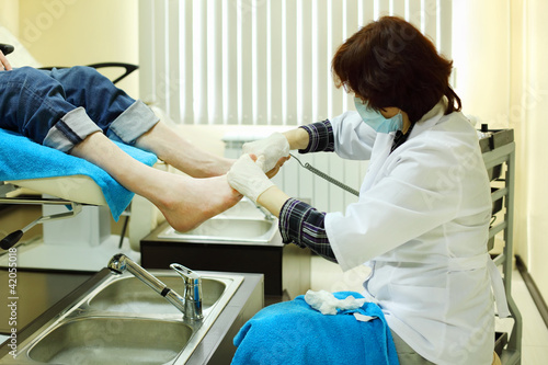 Woman wearing white coat practices chiropody taking care of male