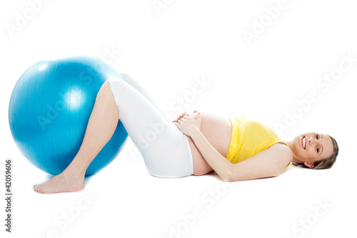 Beautiful pregnant woman lying with exercise ball