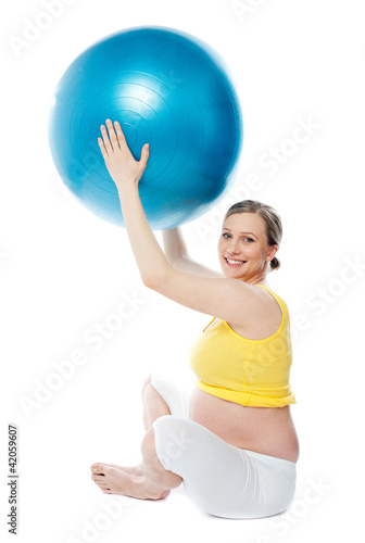 Smiling pregnant woman with a ball
