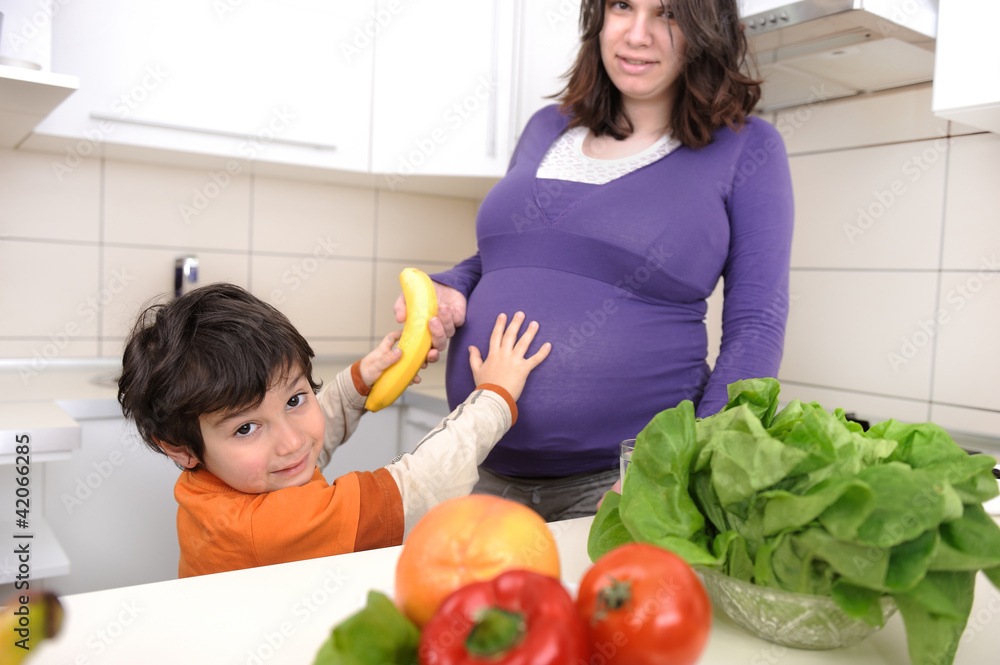 Pregnant woman with her boy in kitchen Pregnant woman with her boy in kitchen