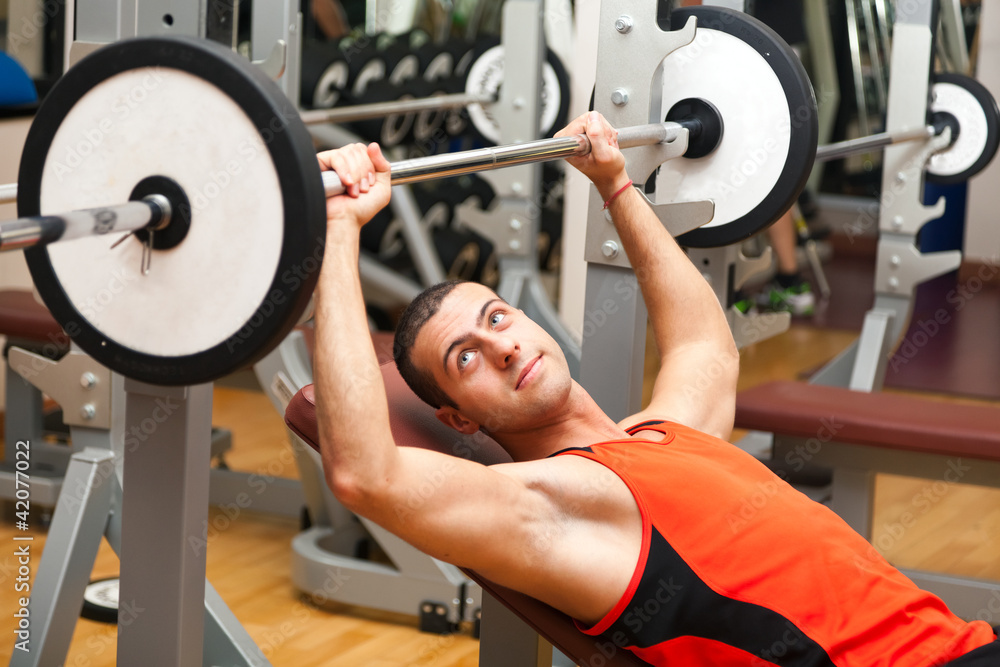 Young man lifting weights in the gym Young man lifting weights in the gym