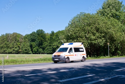 Weißer Krankenwagen auf Landstraße mit Wiesen und Wald, Niedersachsen, Deutschland, Europa