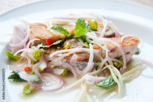 Spicy salad with fried fish and green herb in Thai style
