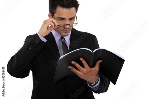 Canvas-taulu Man peering over his glasses and holding a book
